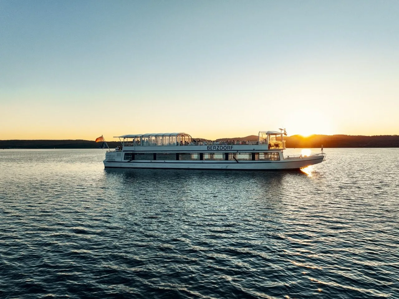 Die EMS Berzdorf gleitet bei Sonnenuntergang über den See